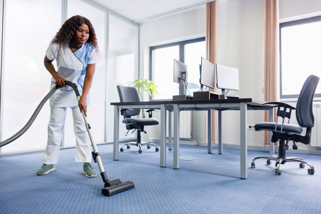 Female worker cleaning a floor with a vacuum cleaner