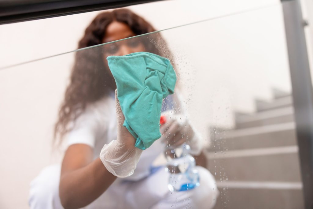 Female worker cleaning glass with green products